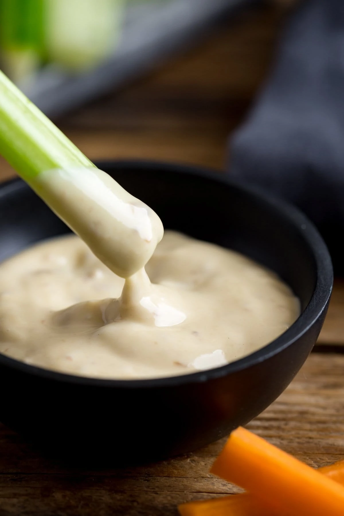 Piece of celery being dipped into a bowl of salad cream