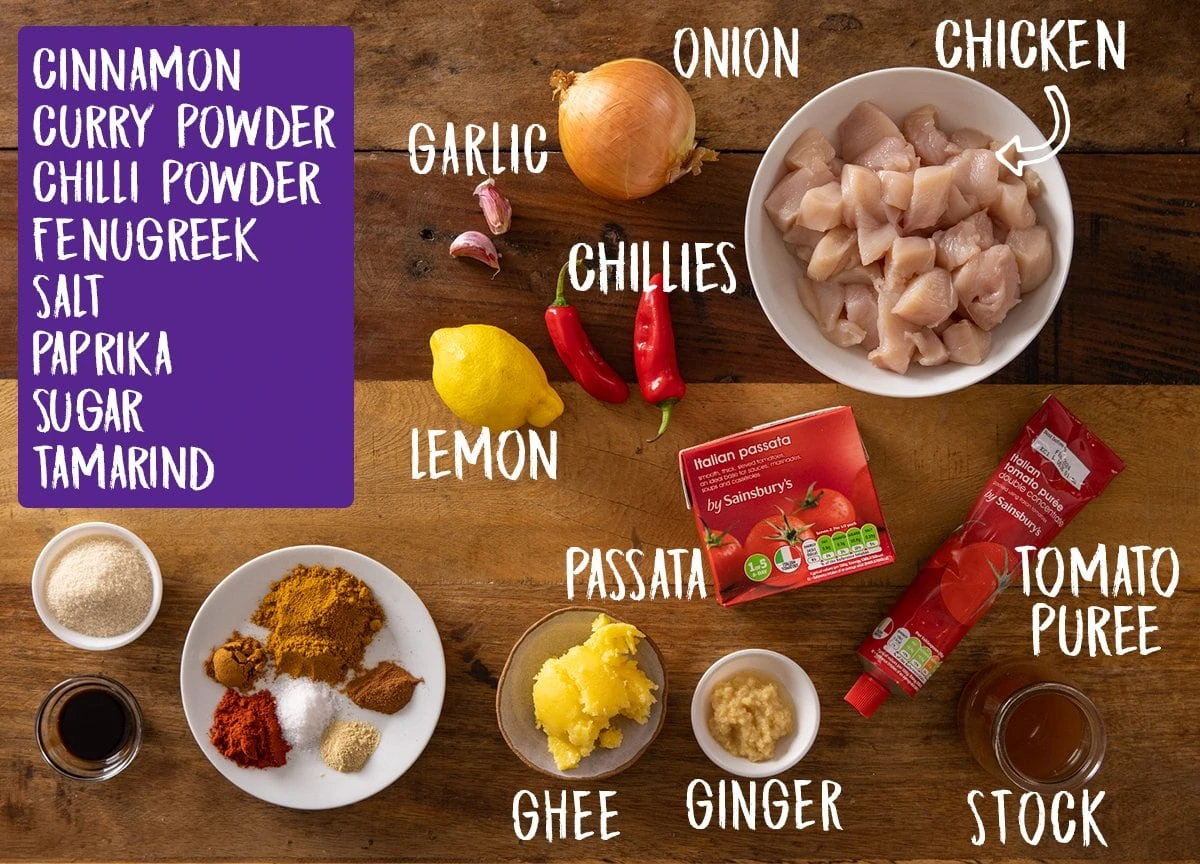 Overhead picture of ingredients for Chicken Pathia Curry on a wooden table.