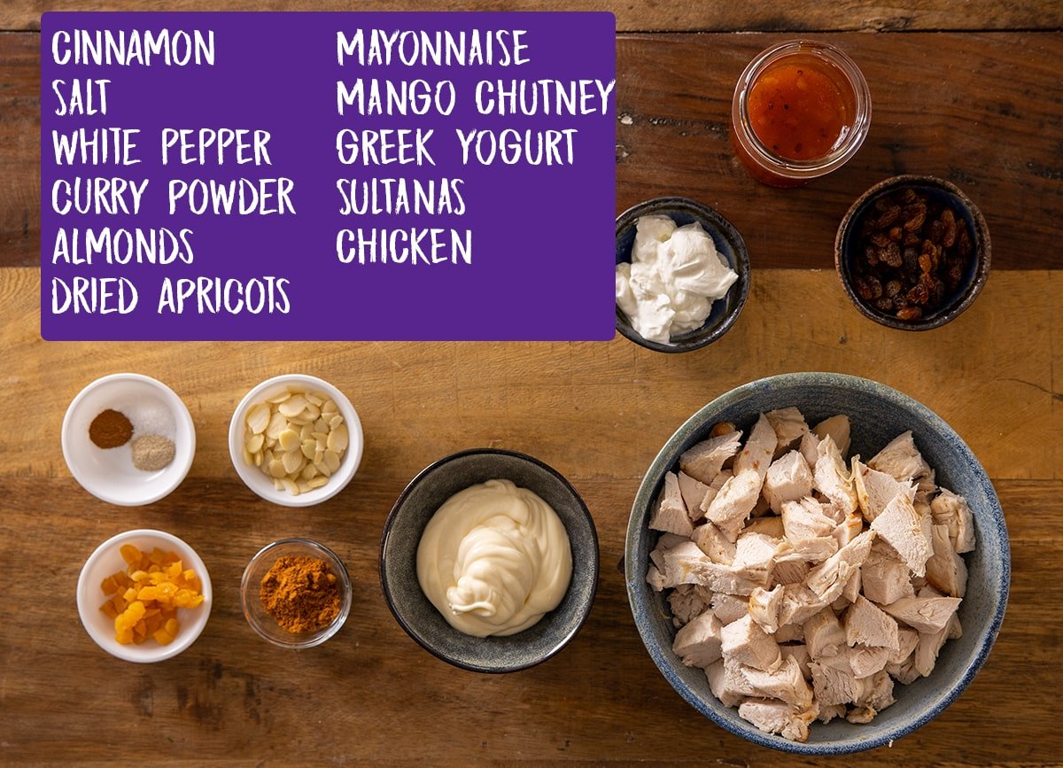 Labelled ingredients for coronation chicken on a wooden background.