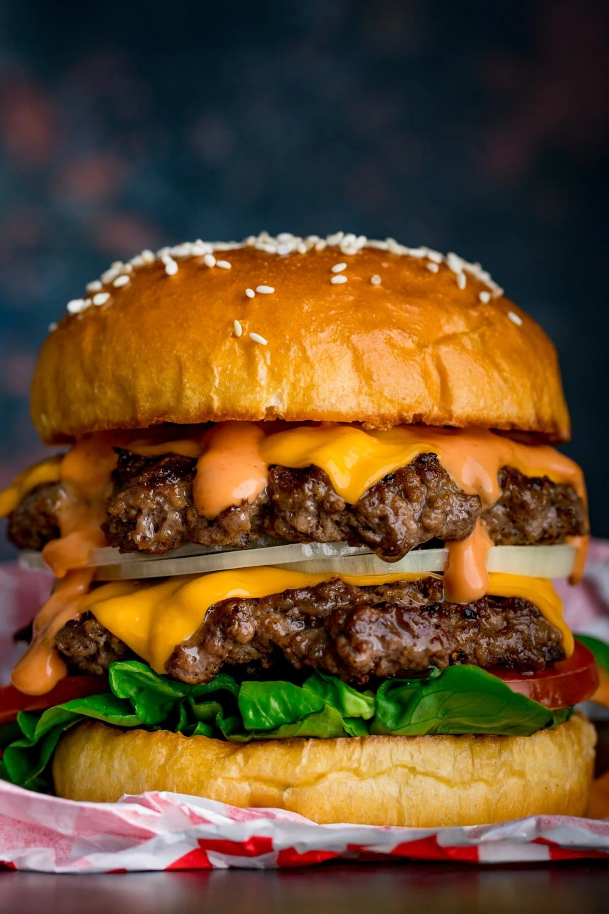 Close up image of a double cheeseburger on a burger wrapper against a dark background.