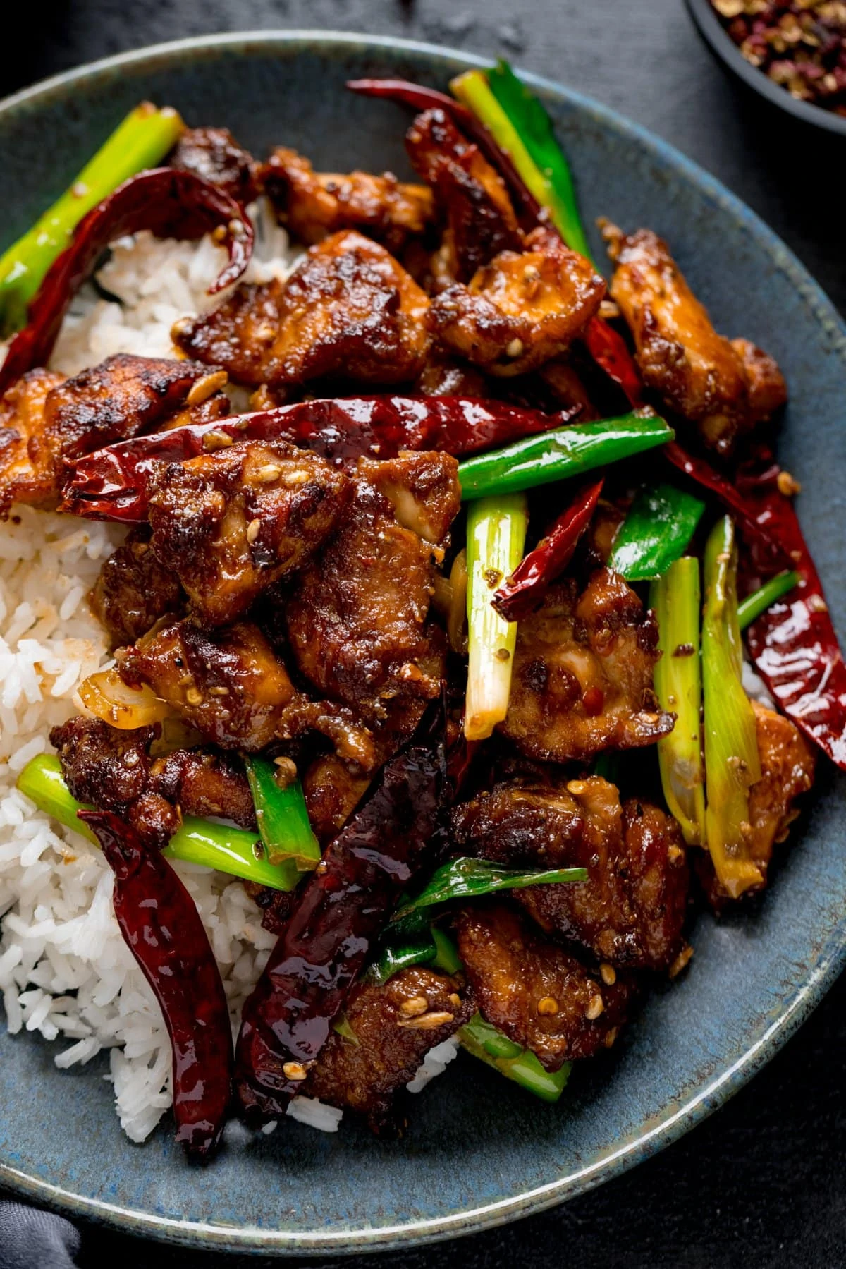 Szechuan chicken and boiled rice on a blue-green plate