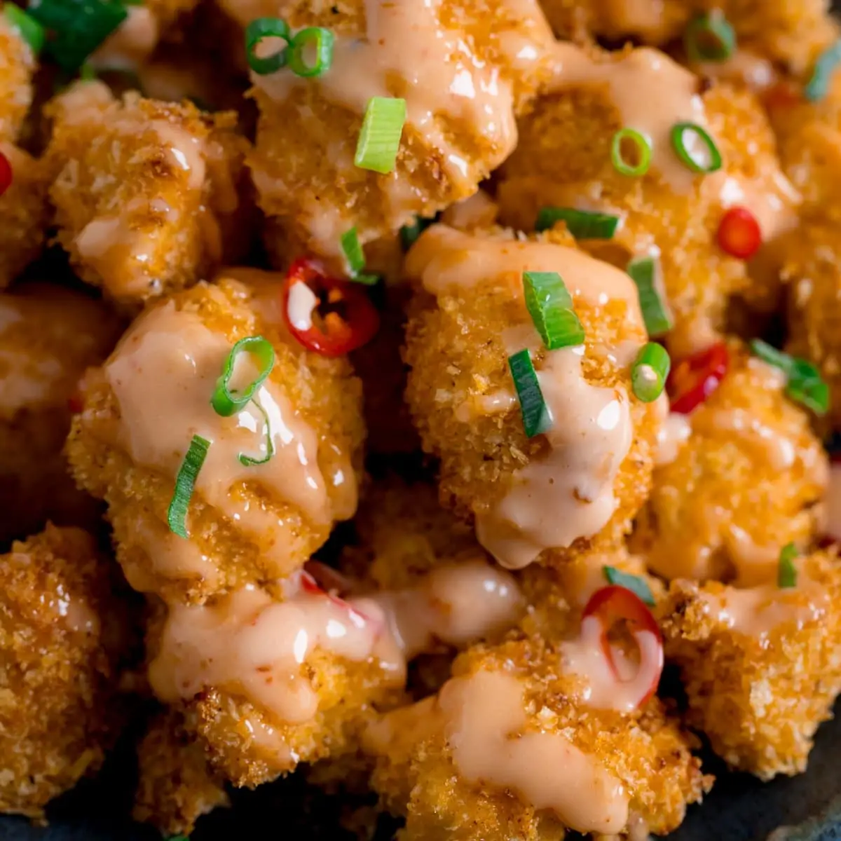 Close up of Crispy Cauliflower with bang bang sauce topped with chillies and spring onions
