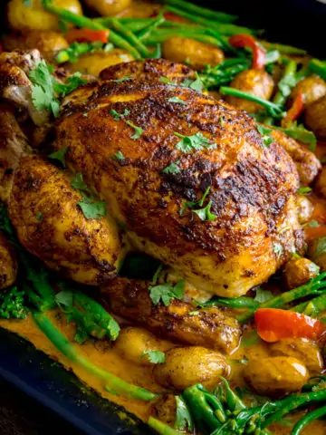 Curry roast chicken in a baking tin with potatoes, vegetables and curry sauce.