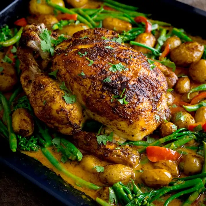 Curry roast chicken in a baking tin with potatoes, vegetables and curry sauce.