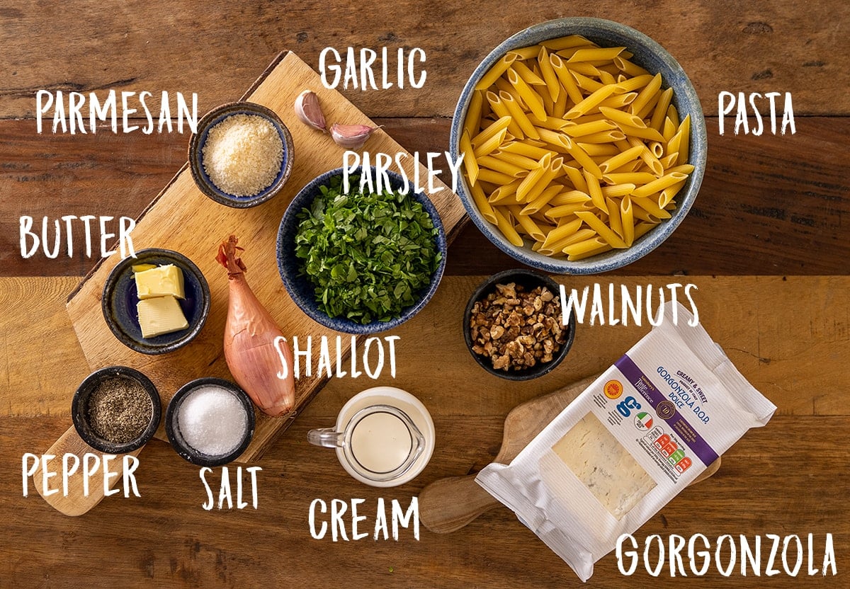 Labelled ingredients for making gorgonzola pasta on a wooden board.