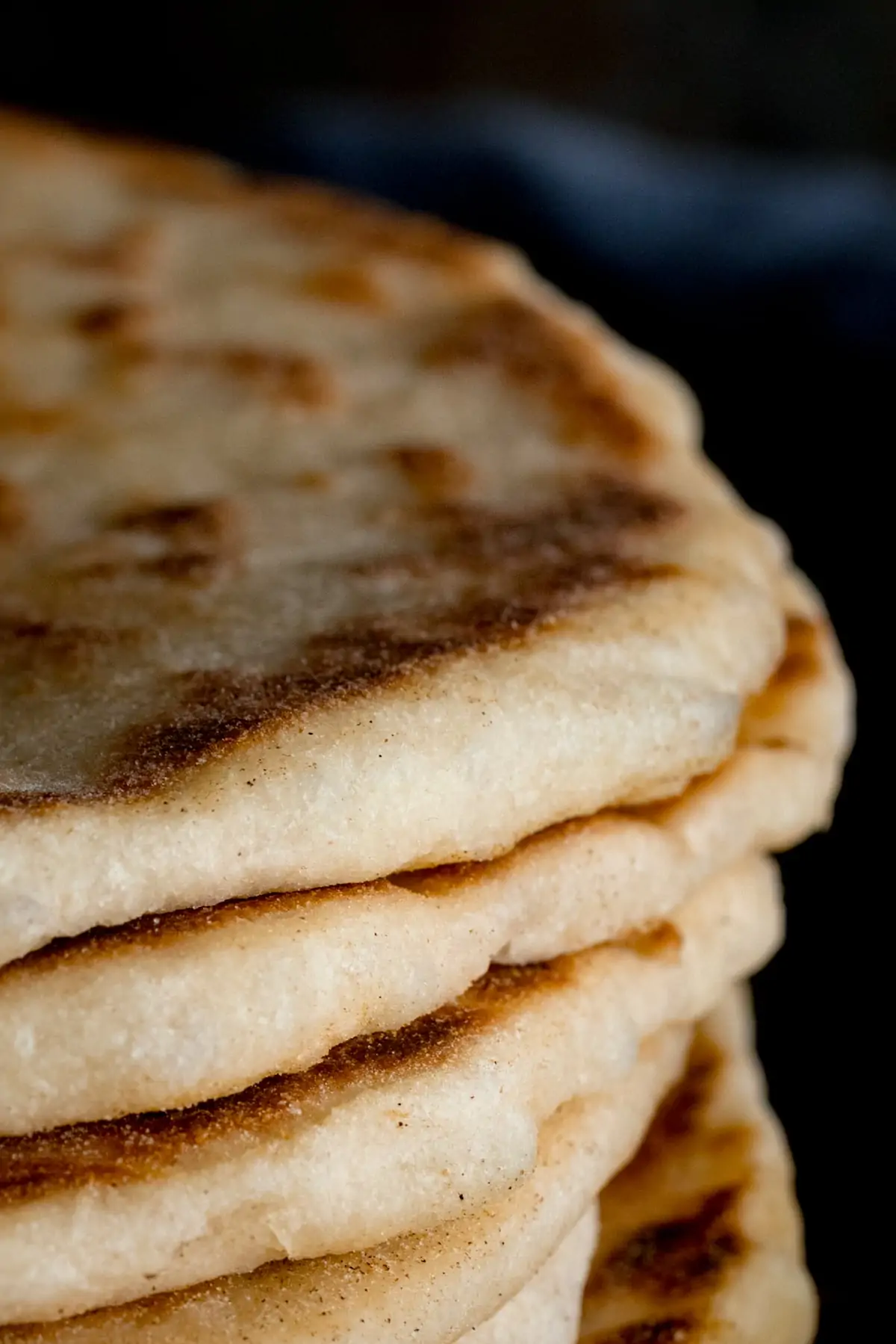 Close up of the edge of a stack of flatbreads, against a dark background.