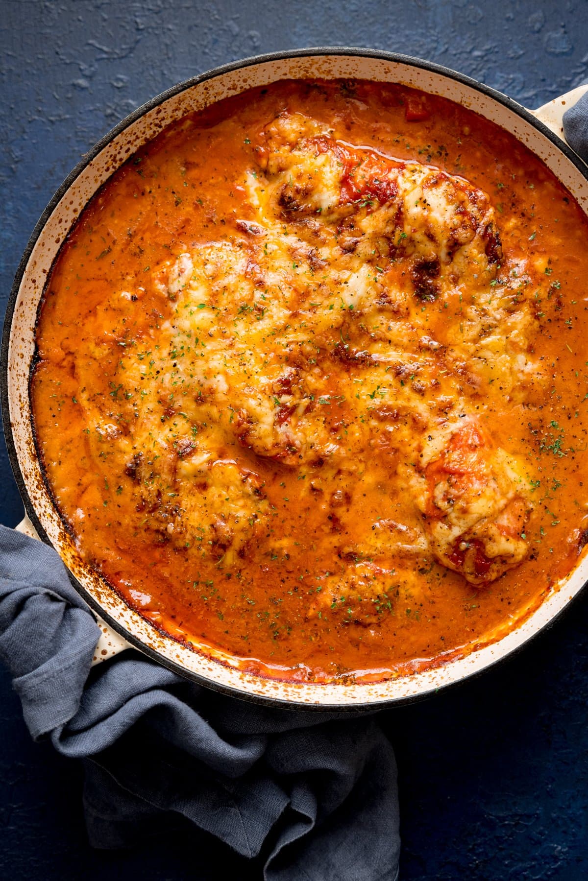 Overhead image of lasagne-style chicken bake in a large pan on a blue background.