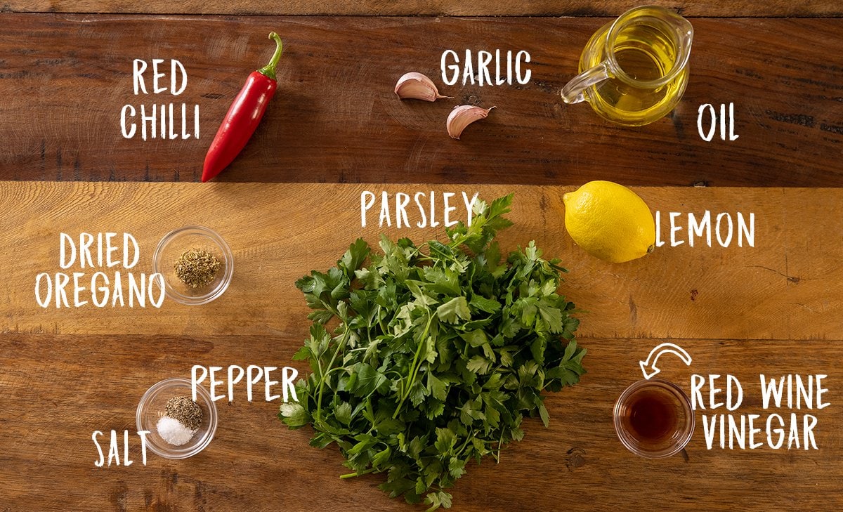 Overhead photo of ingredients for making a chimichurri sauce on a wooden board.