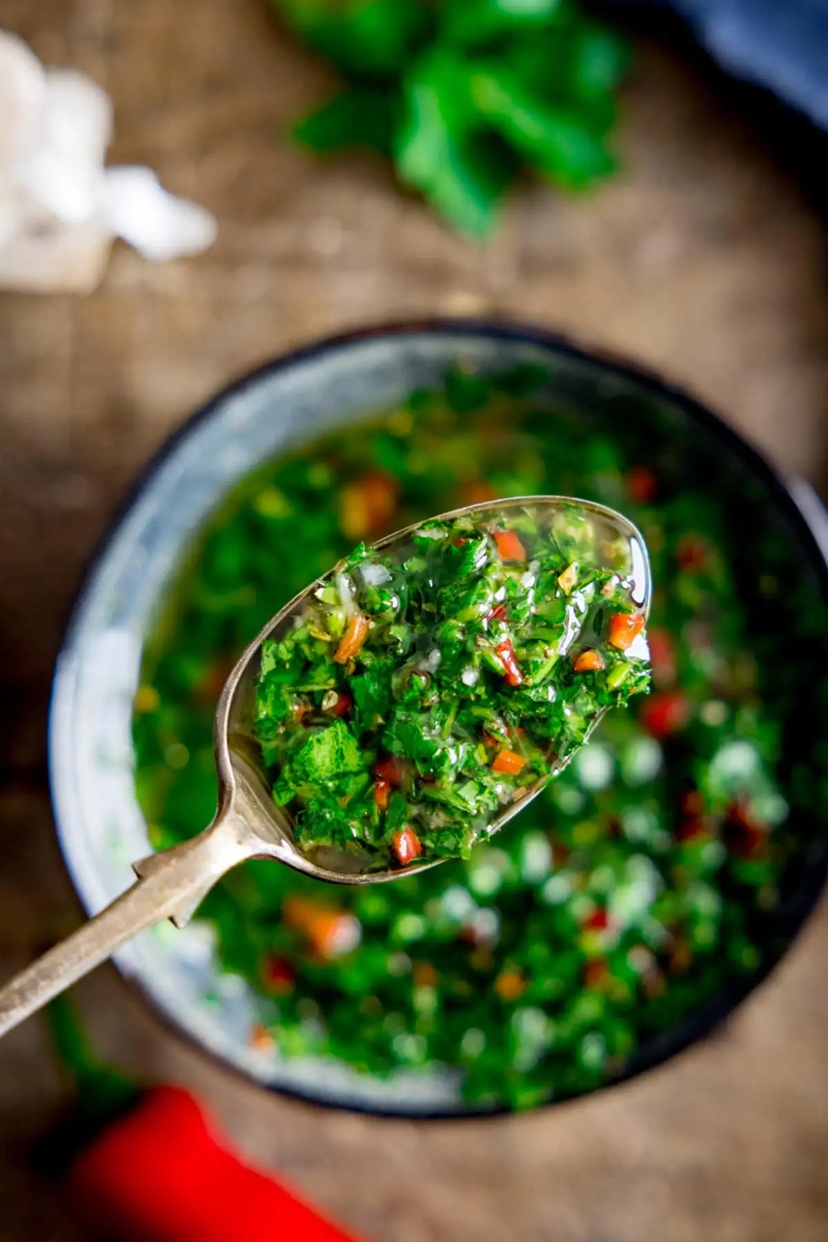 A close up of a spoon full of chimichurri sauce.