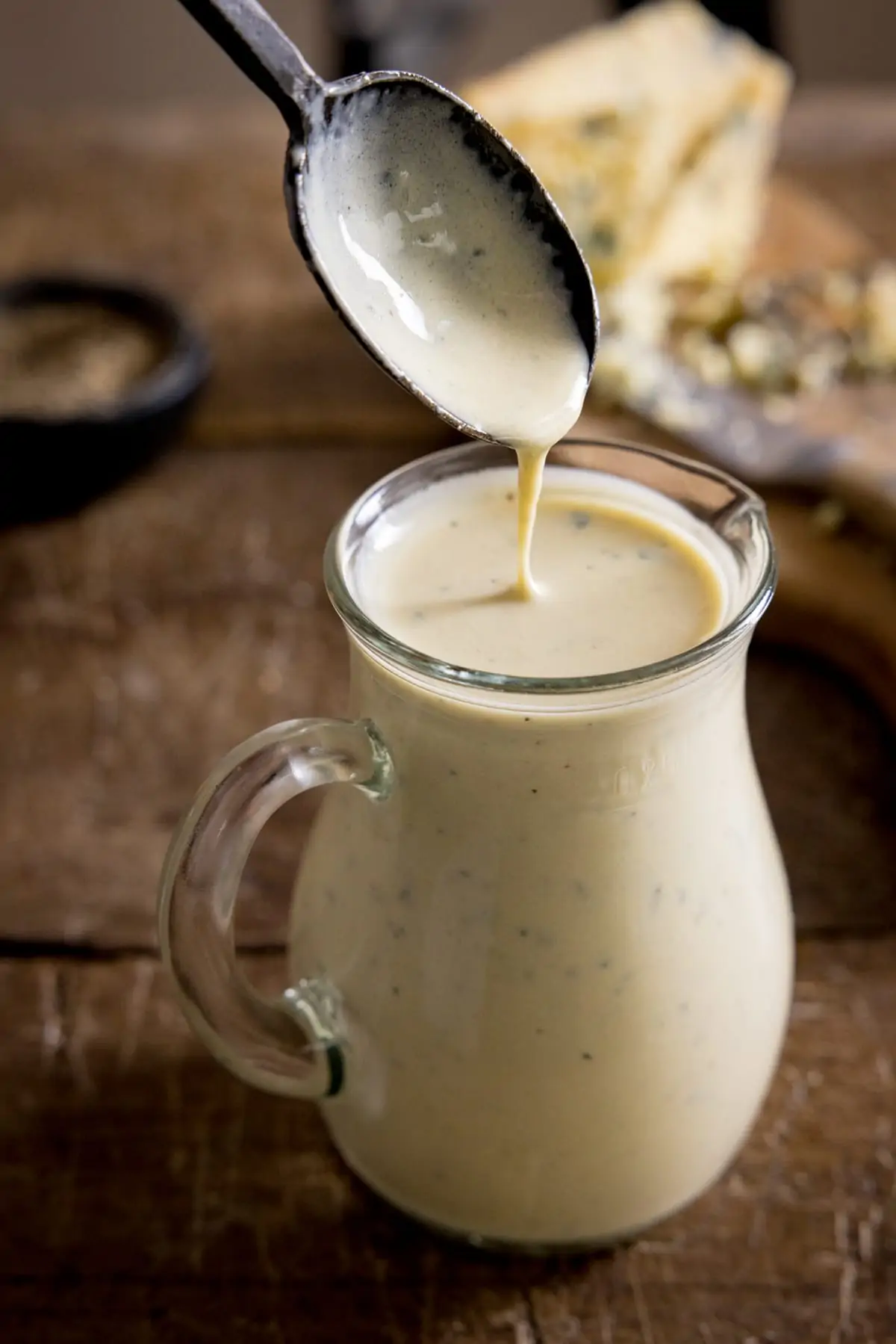 Some blue cheese sauce being spooned into a jug for serving.