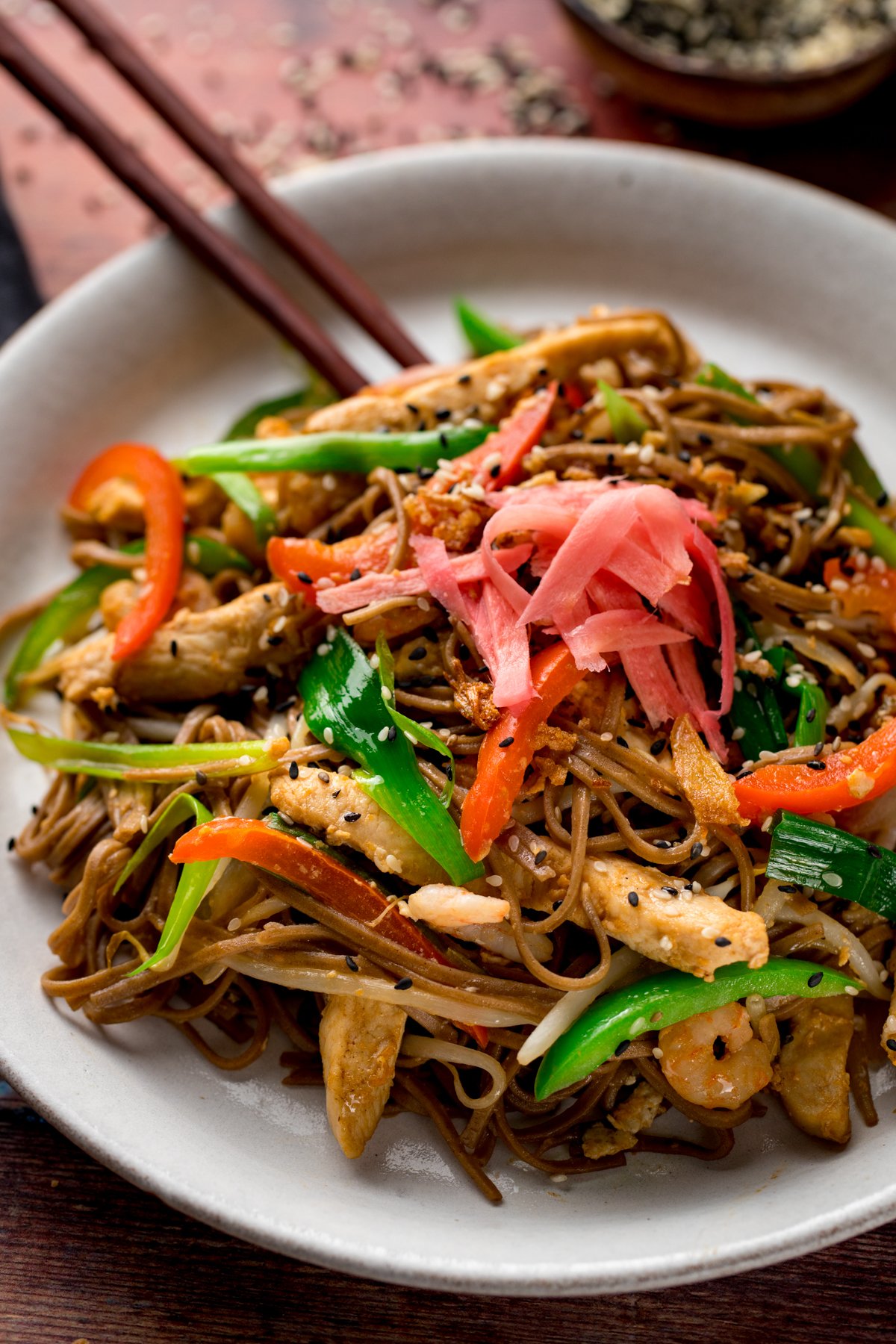 A close up of chicken yakisoba with some chopsticks on a white plate