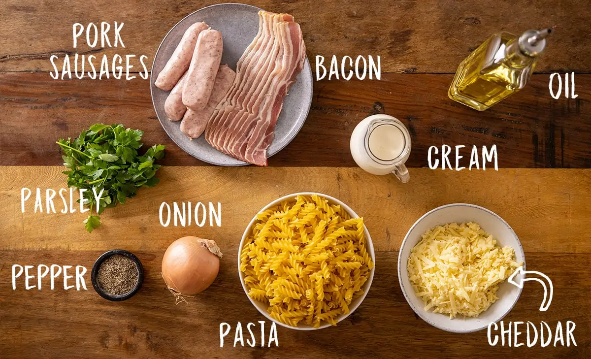 Ingredients for creamy sausage pasta recipe on a wooden table.