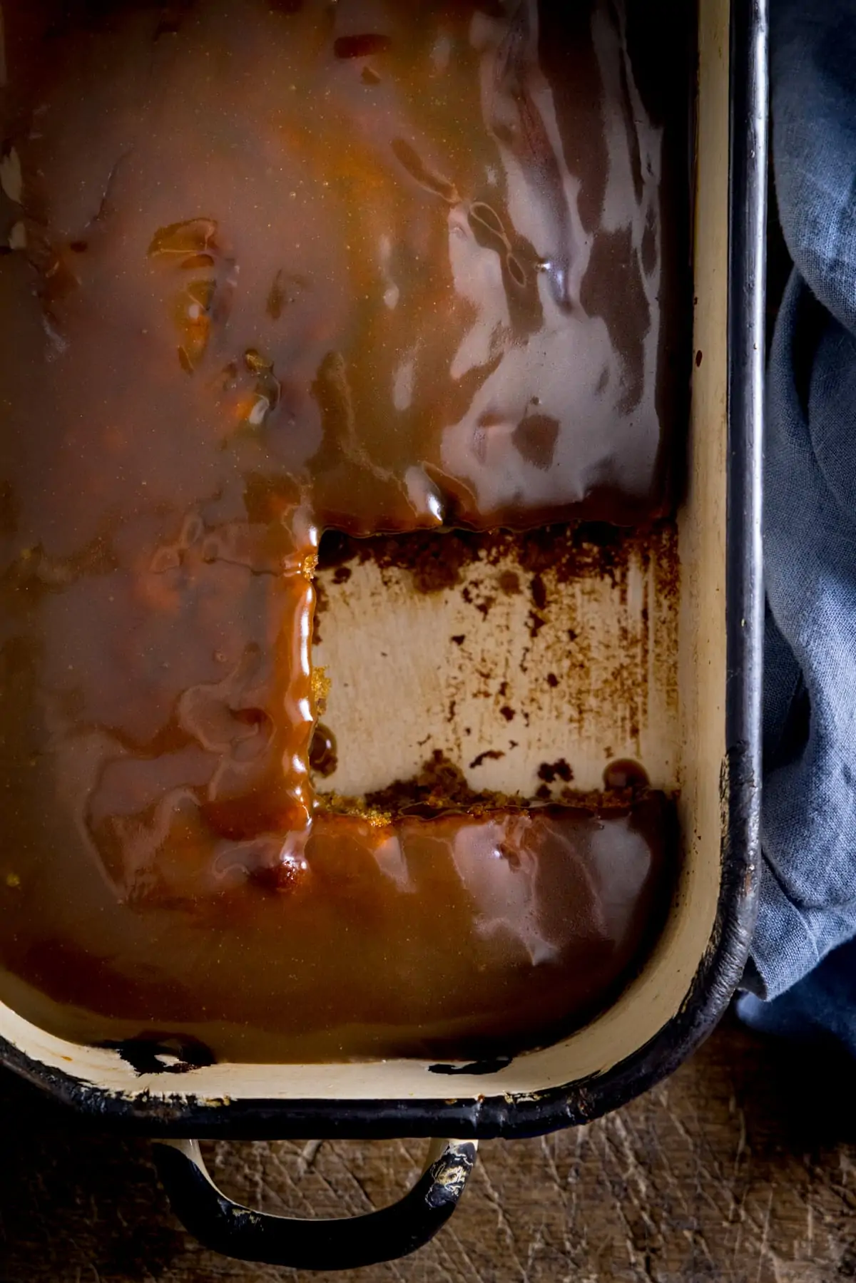 Overhead of sticky toffee pudding with a piece taken out.