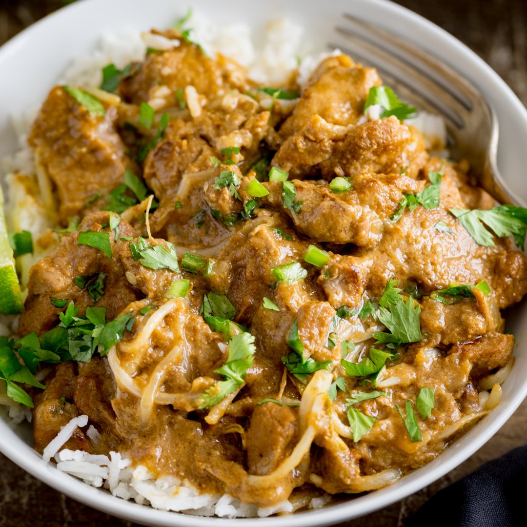 A close up photo of Thai Style Peanut Pork in a white bowl with a sprinkling of fresh coriander.