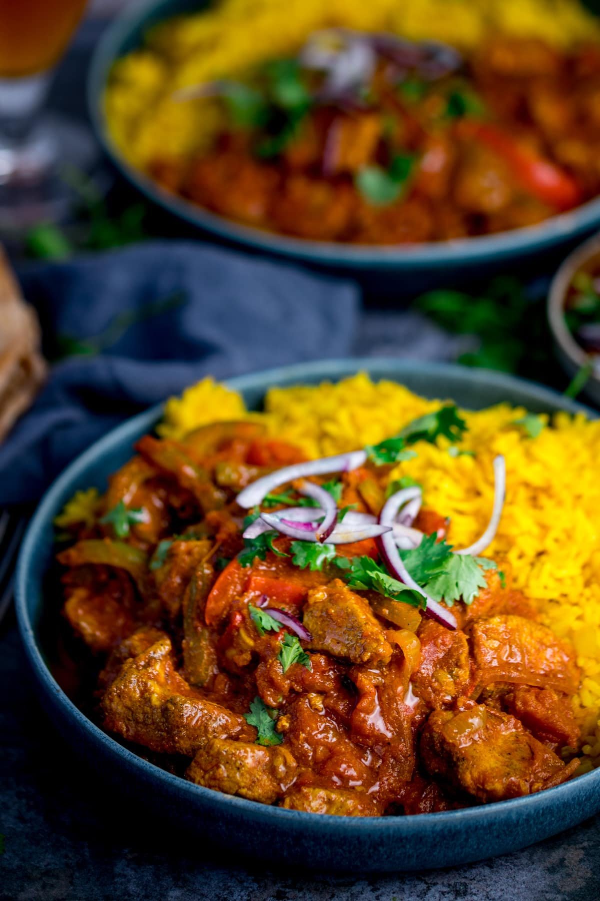 Chicken Jalfrezi with pilau rice. Red onion and coriander sprinkled on top.