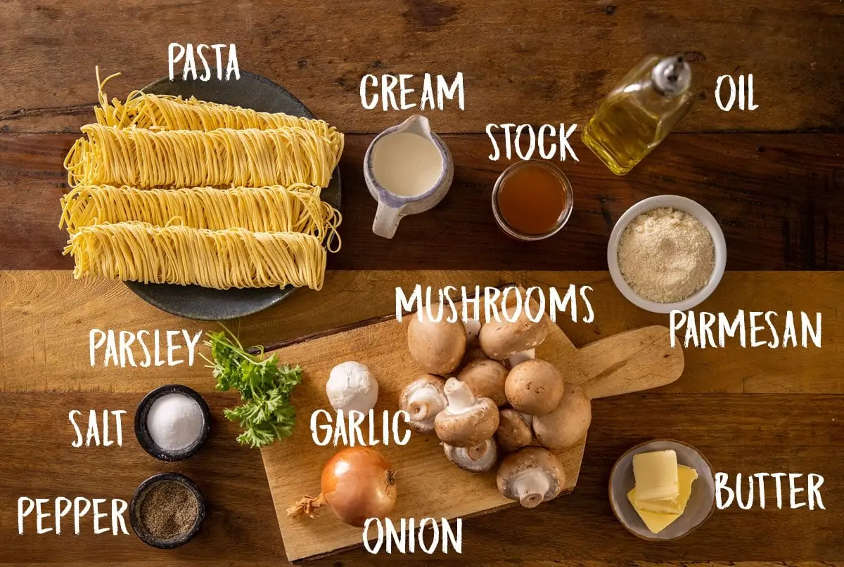 All of the ingredients for creamy mushroom pasta laid out separately on a wooden table