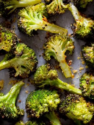 A square photo of roasted broccoli with garlic on a white tray