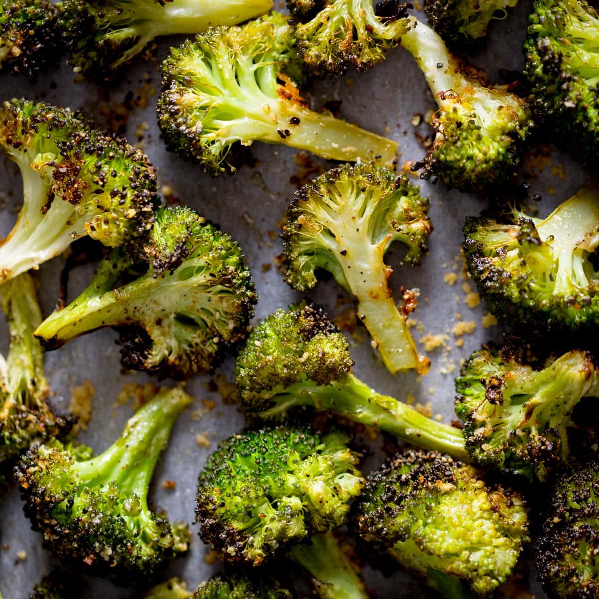 A square photo of roasted broccoli with garlic on a white tray
