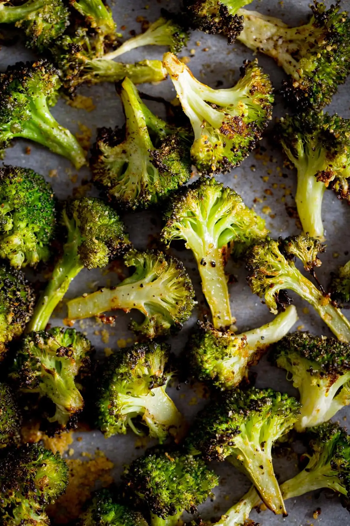 Roasted broccoli with garlic spread out on a white tray