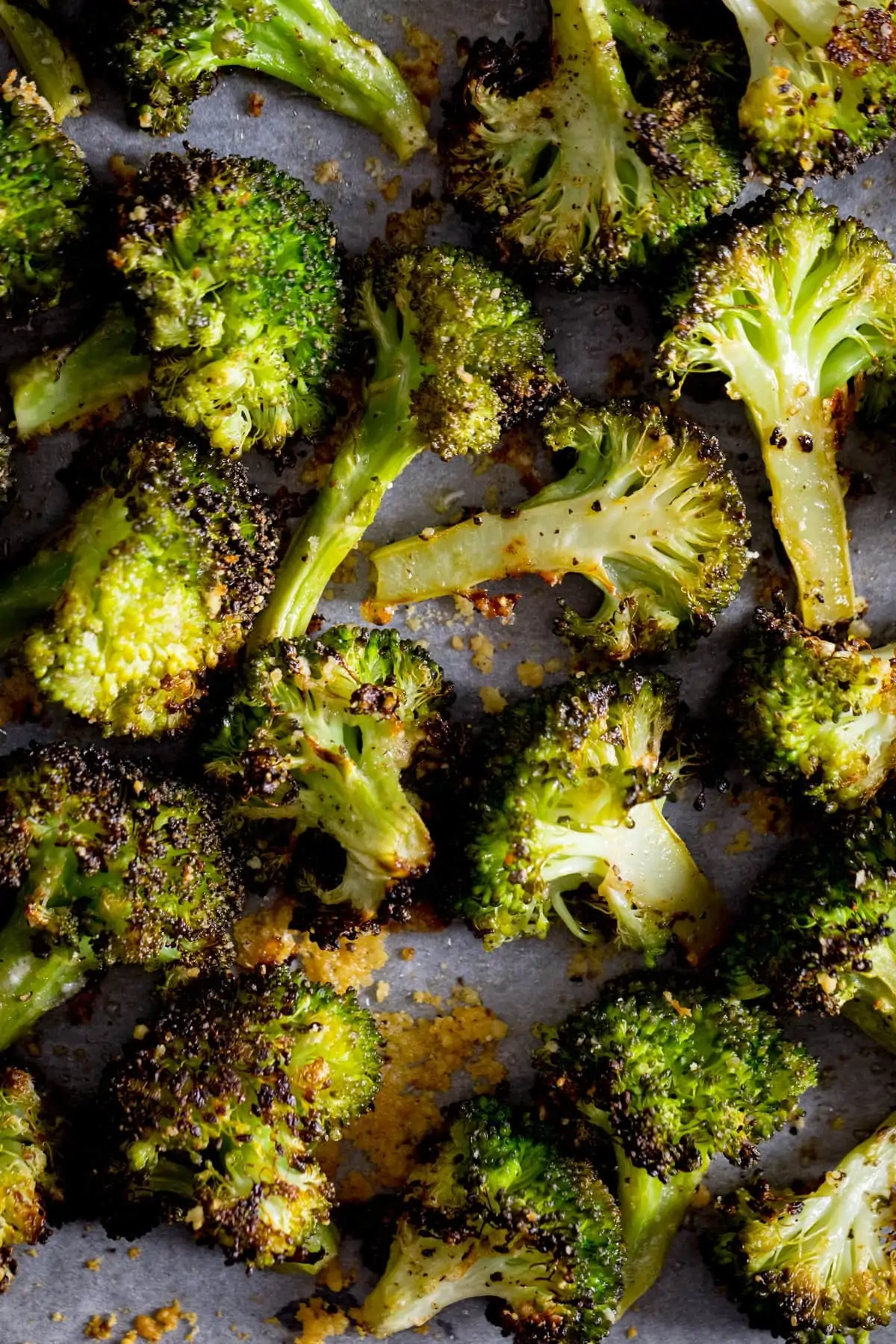 A close up of roasted broccoli with garlic on a white tray