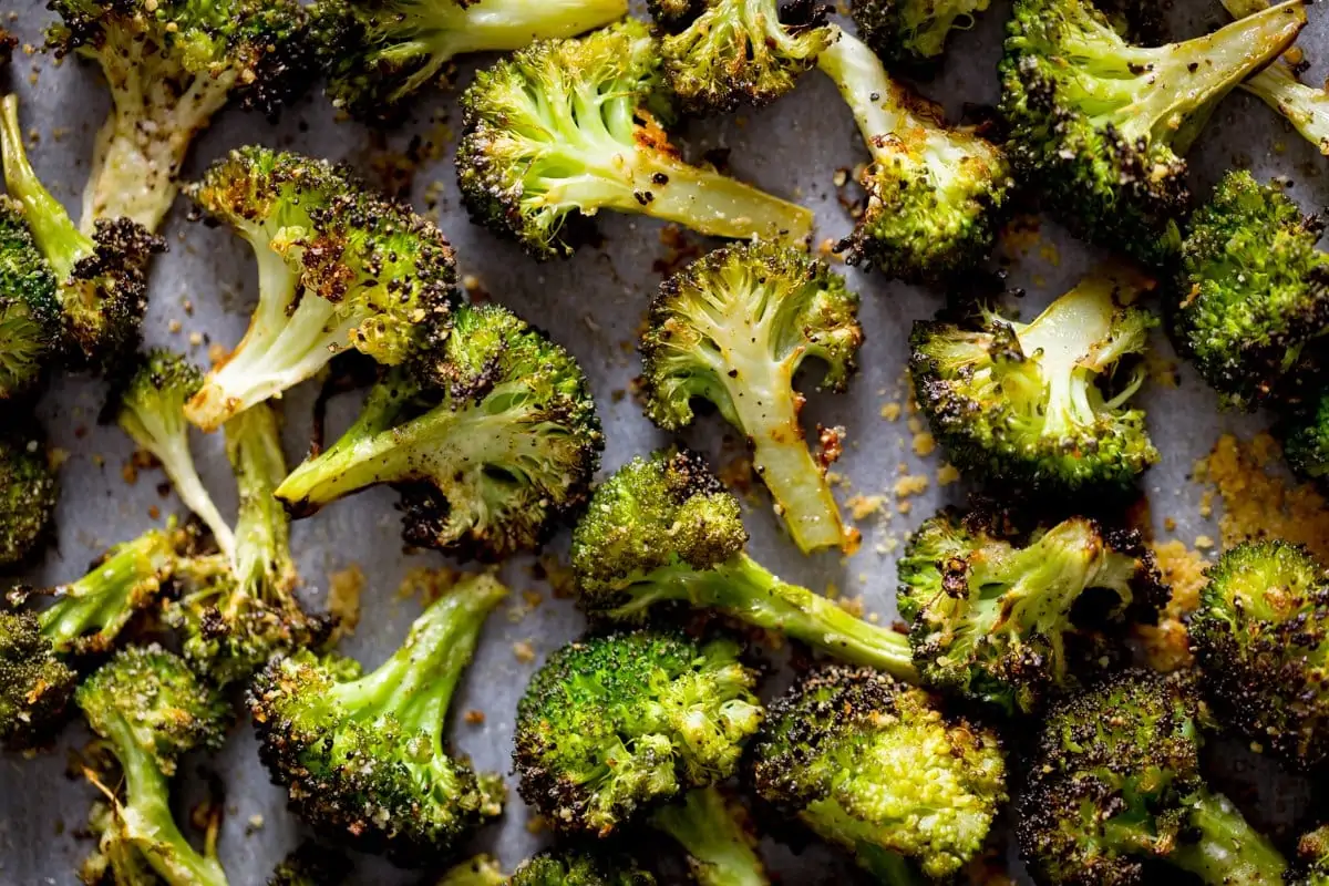 Roasted broccoli with garlic spread out on a white tray