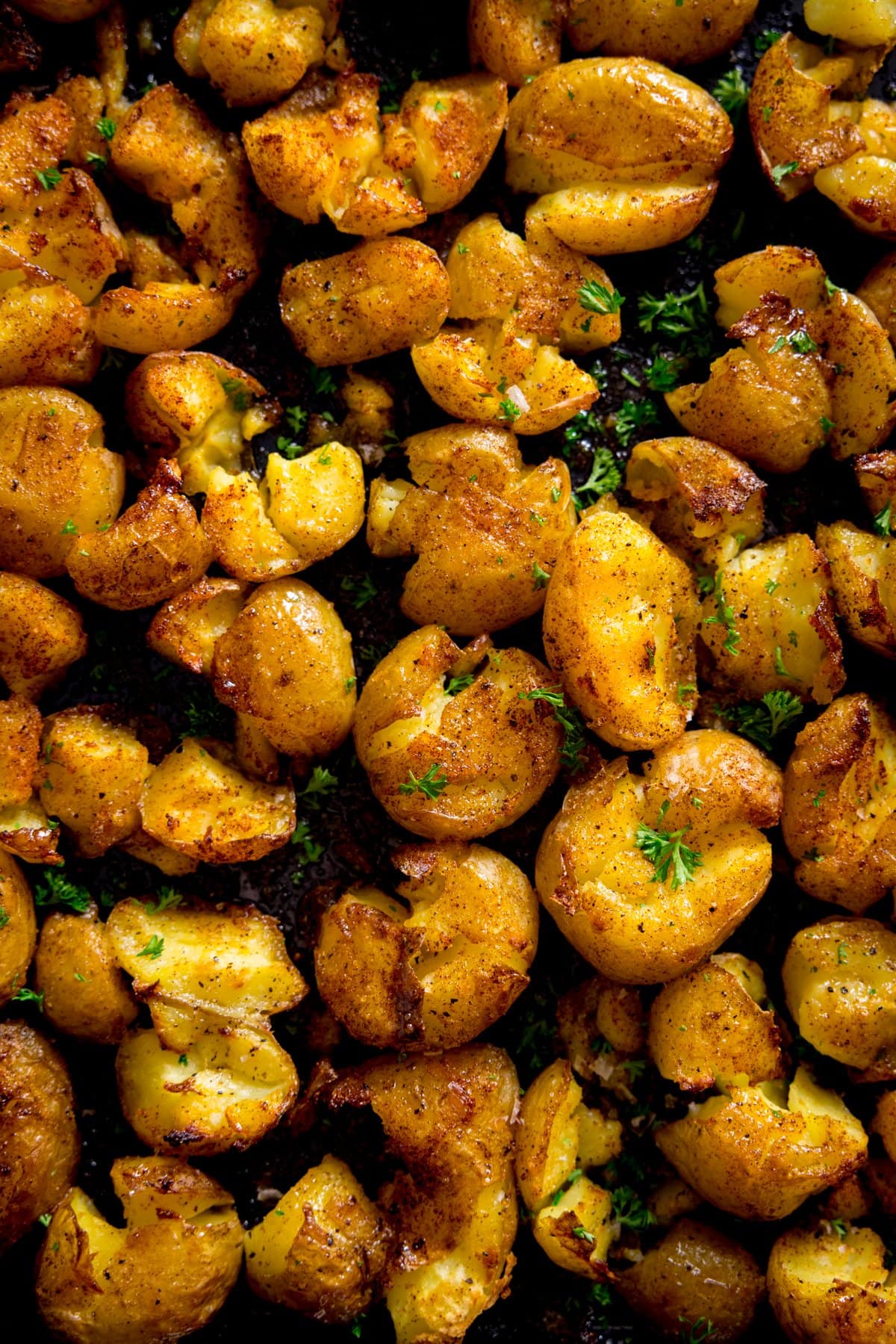A tray of crispy smashed potatoes sprinkled with parsley