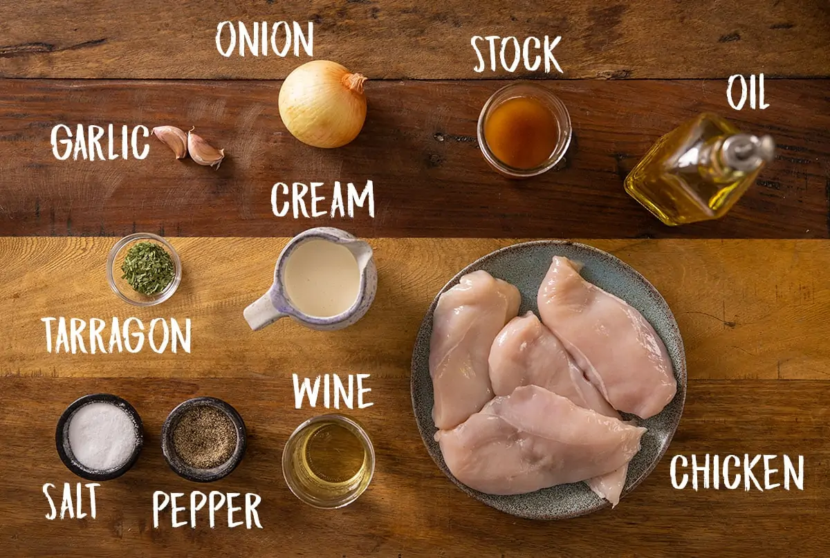 A wooden table with all of the ingredients for Tarragon Chicken laid out separately.