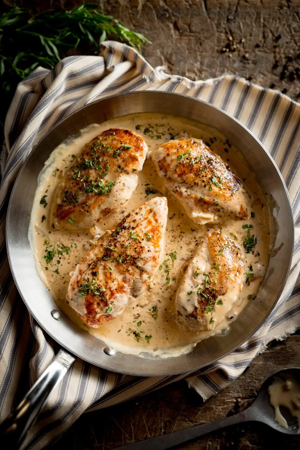 A photo looking down on a pan of cooked Tarragon Chicken, on a stripy tea towel