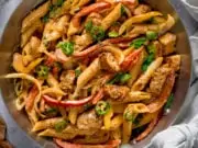 Square image of buffalo chicken pasta in a silver pan on a light grey background.