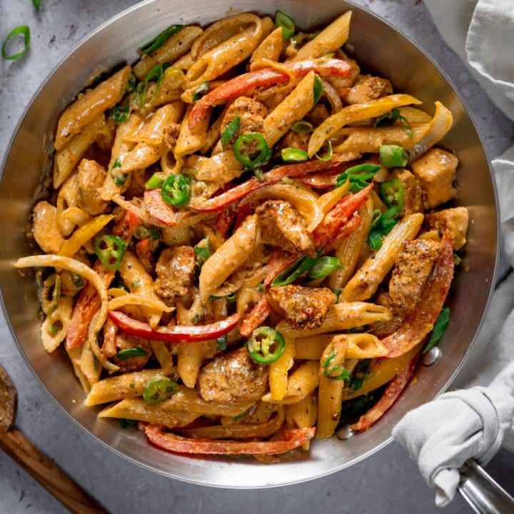 Square image of buffalo chicken pasta in a silver pan on a light grey background.