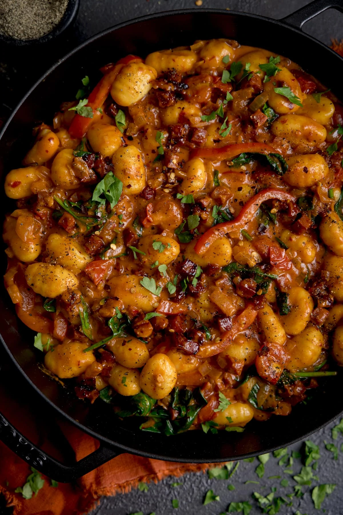 Close up overhead of a pan filled with gnocchi and chorizo in harissa sauce.
