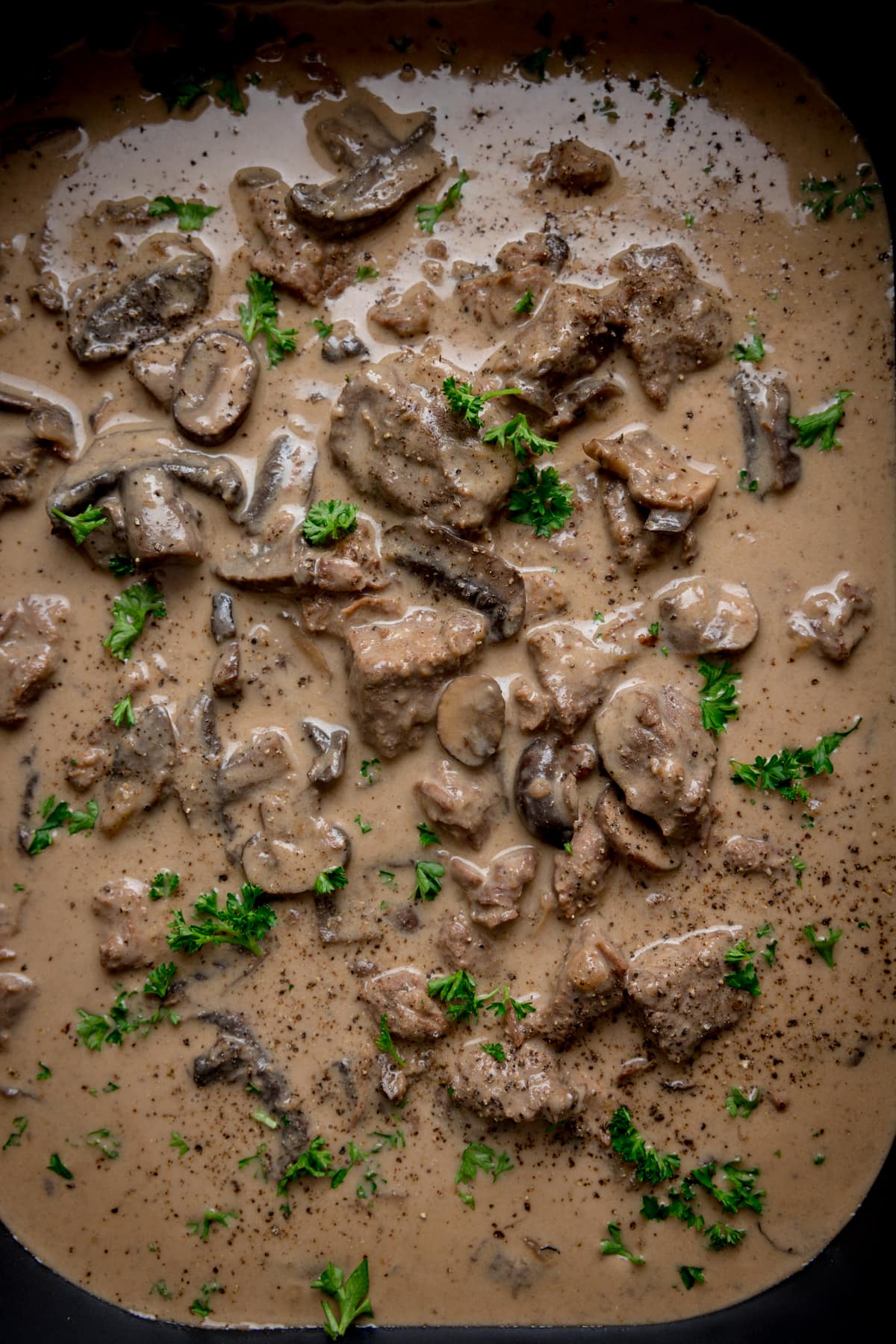 Overhead close up of slow cooker beef stroganoff with parsley sprinkled on top.