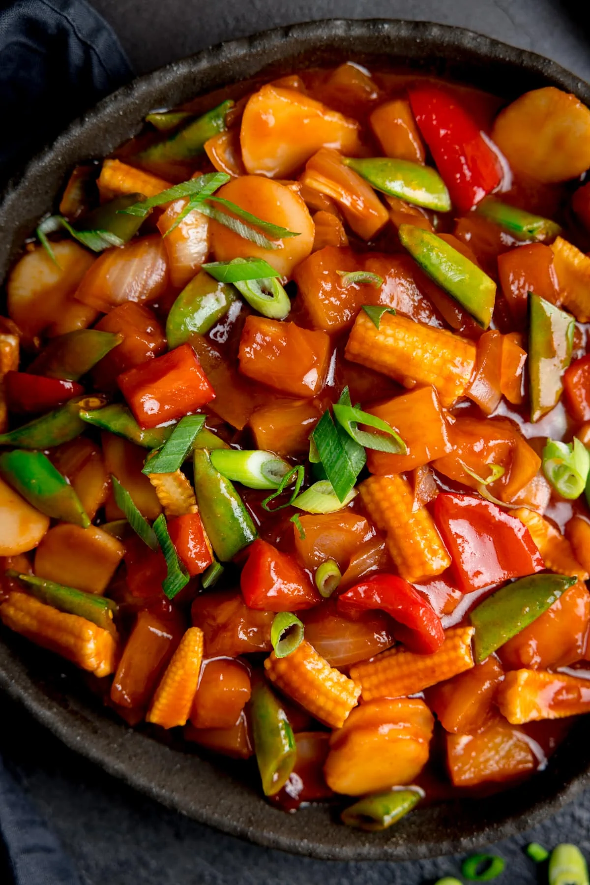 Close up overhead shot of sweet and sour vegetables in a black serving bowl.