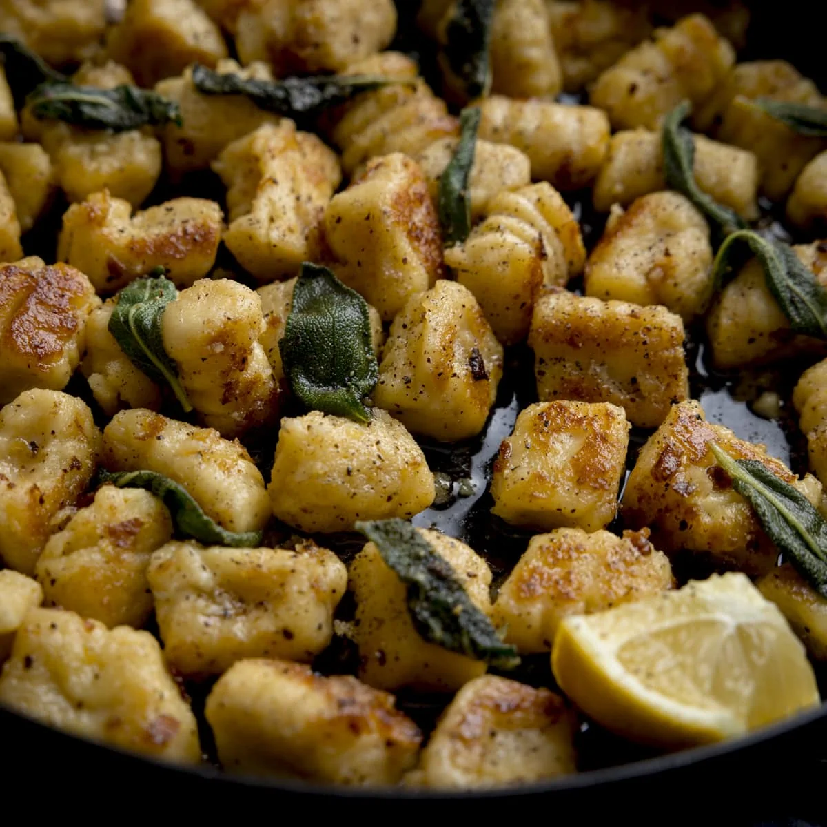 Close up of gnocchi with brown butter and sage in a pan with lemon