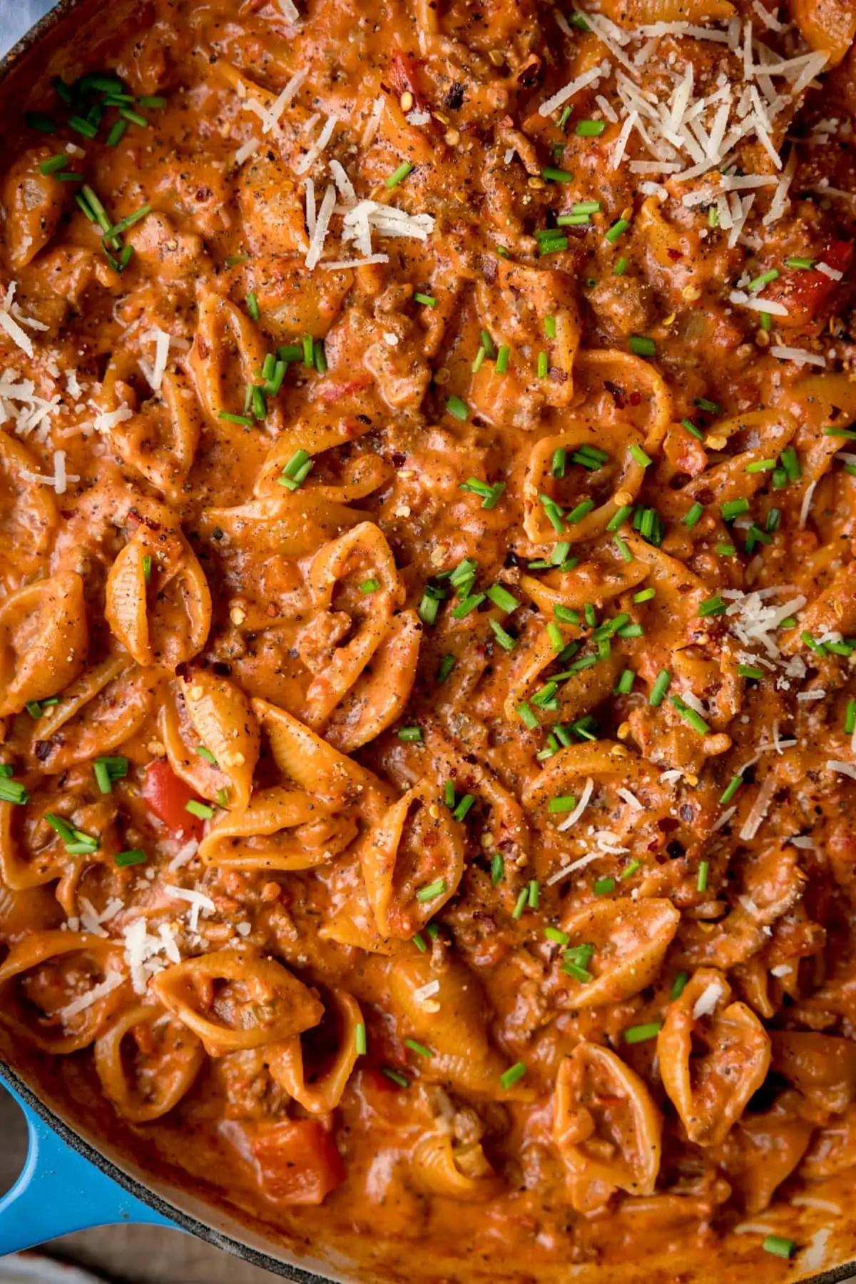 Overhead image of bolognese pasta in a pan, topped with chives.