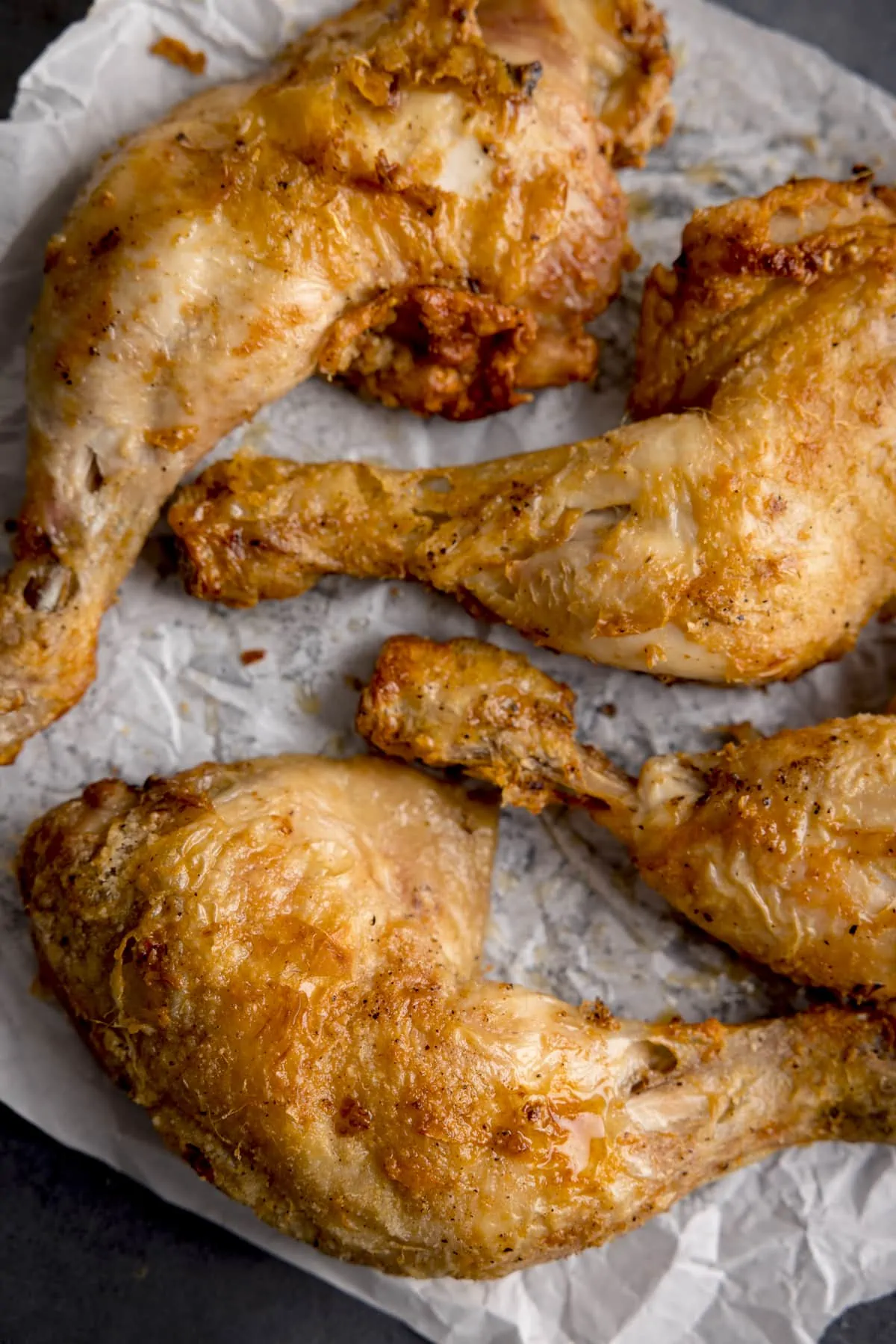 Overhead image of crispy chicken thighs on a piece of baking parchment.