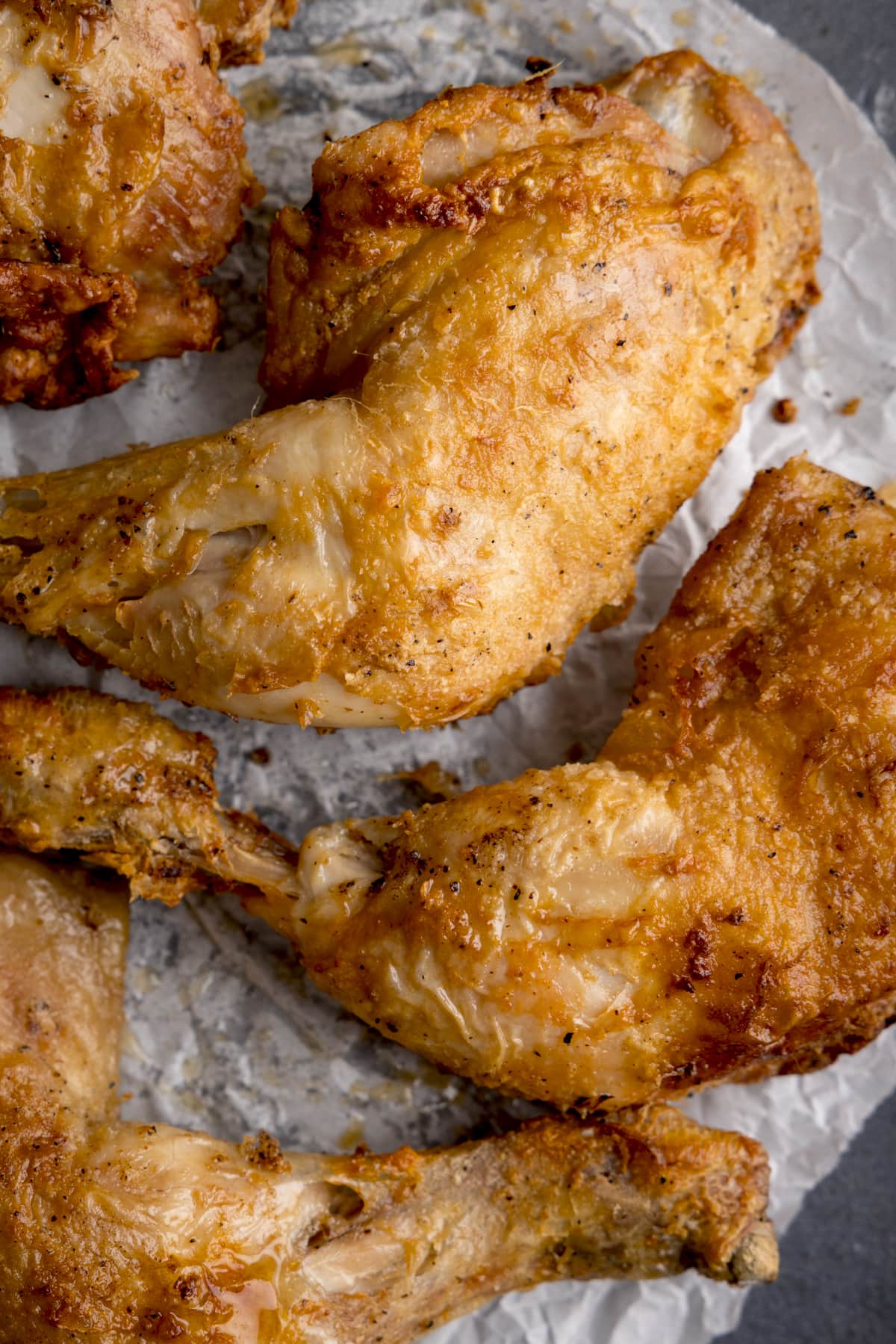 High overhead image of air fried, crispy chicken thighs on a piece of parchment paper.