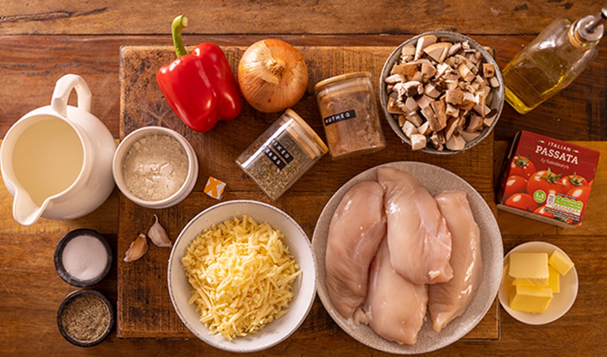 Ingredients for lasagne style chicken bake on a wooden board.