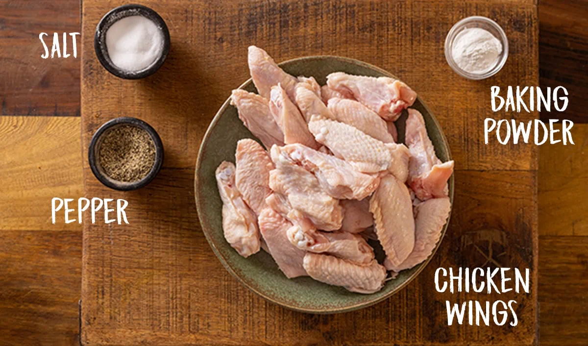 Ingredients for crisp chicken wings on a wooden table