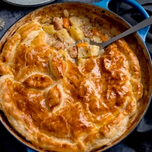 Square image of a sausage and mustard pie - shot from overhead. There is a spoonful of the pie filling being taken out.