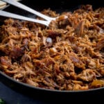 Square image of a pan of pork carnitas being fried.