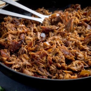 Square image of a pan of pork carnitas being fried.