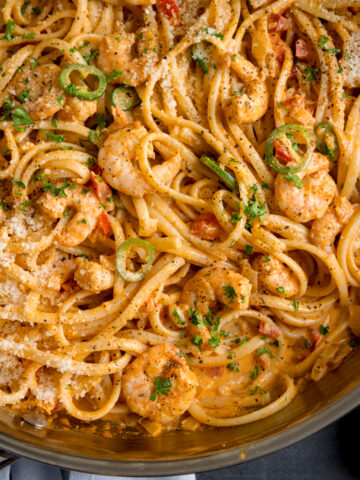 square overhead image of a pan of prawn linguine in a creamy buffalo sauce.