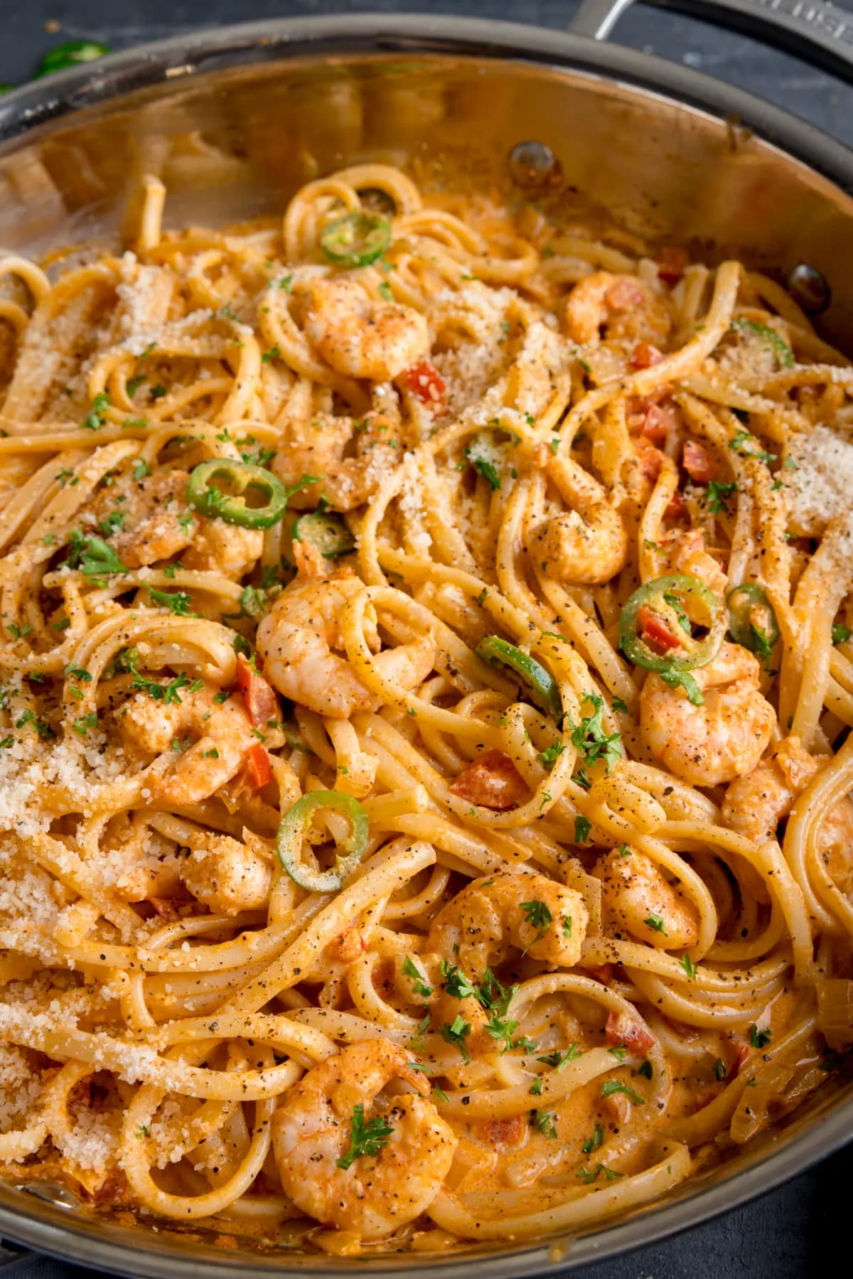Tall close-up image of a pan of prawn linguine in a creamy buffalo sauce.