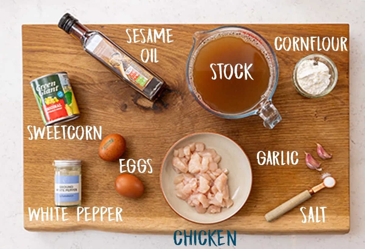Ingredients for chicken and sweetcorn soup on a wooden board.