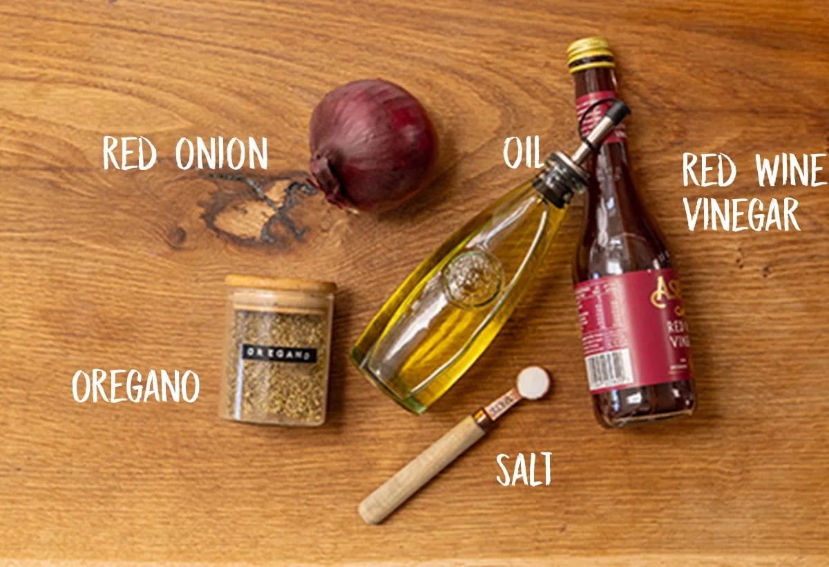 Ingredients for marinated onions on a wooden board.