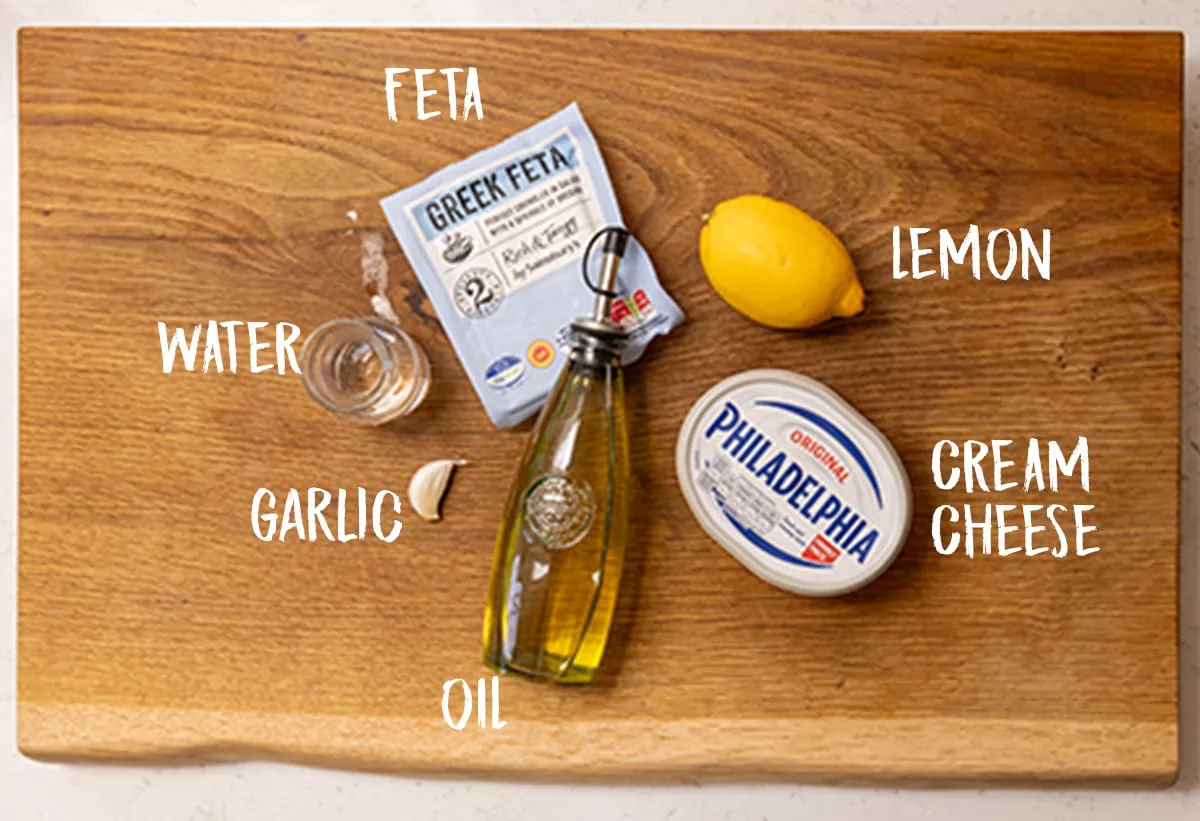 Ingredients for whipped feta on a wooden board.