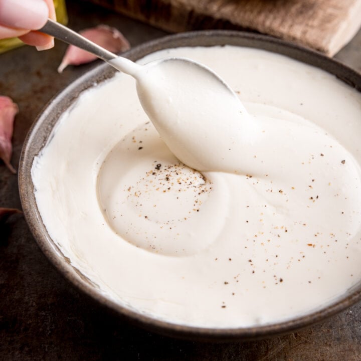 Whipped feta in a dark bowl being stirred.