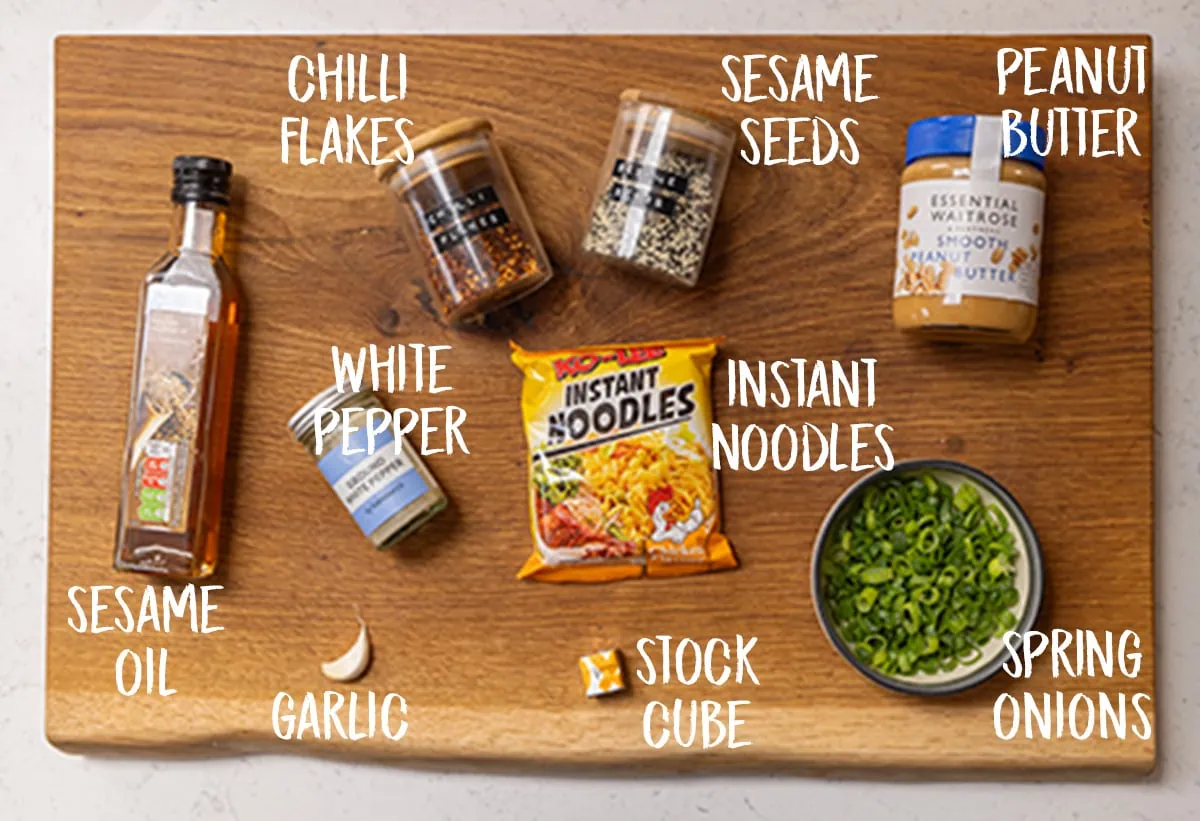 Ingredients of peanut butter ramen noodles on a wooden board.