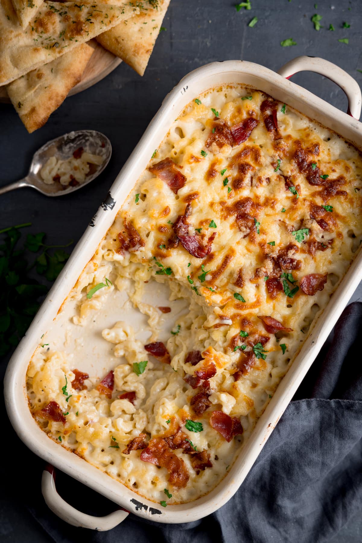 Overhead picture of a casserole dish with mac n cheese in sat on a slate grey board.